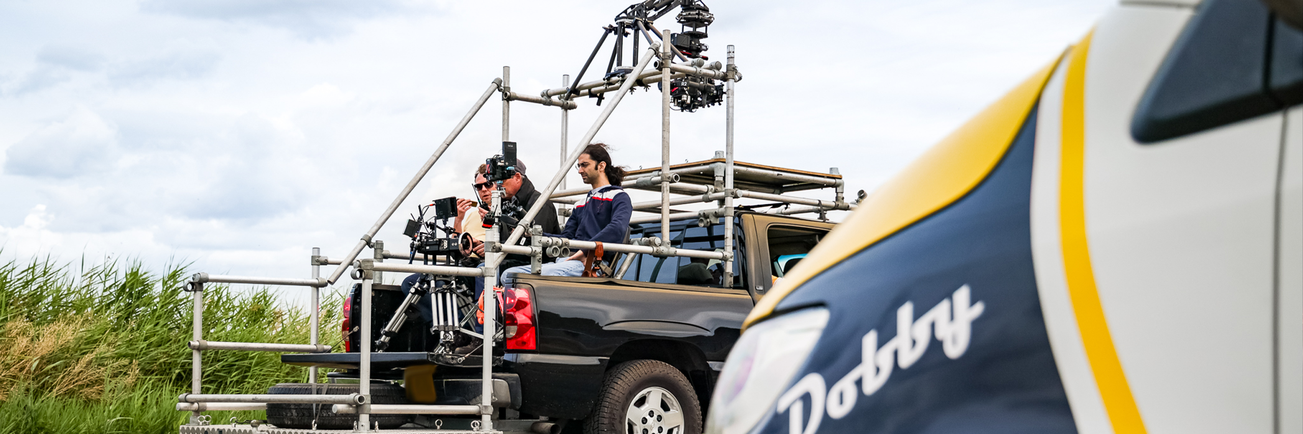 TV Film Production Crew Sitting on the Back of a Camera Car